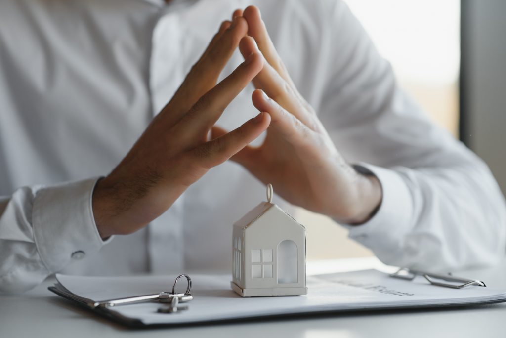 Manos de persona sobre la figura de una casa y unas llaves prepara su speech de ventas